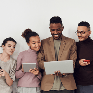 four people looking and smiling at laptop man is holding