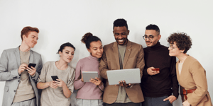 group of individuals smiling at a tablet in one person's hand