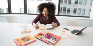 woman at desk with open books and laptop