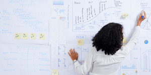 women drawing formulas and graphs all over a whiteboard