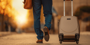 close photo of walking legs and suitcase outside at sunset